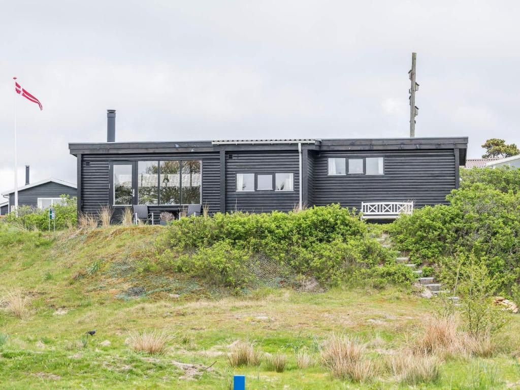 een zwart huis bovenop een heuvel bij Holiday home Fanø CXC in Fanø