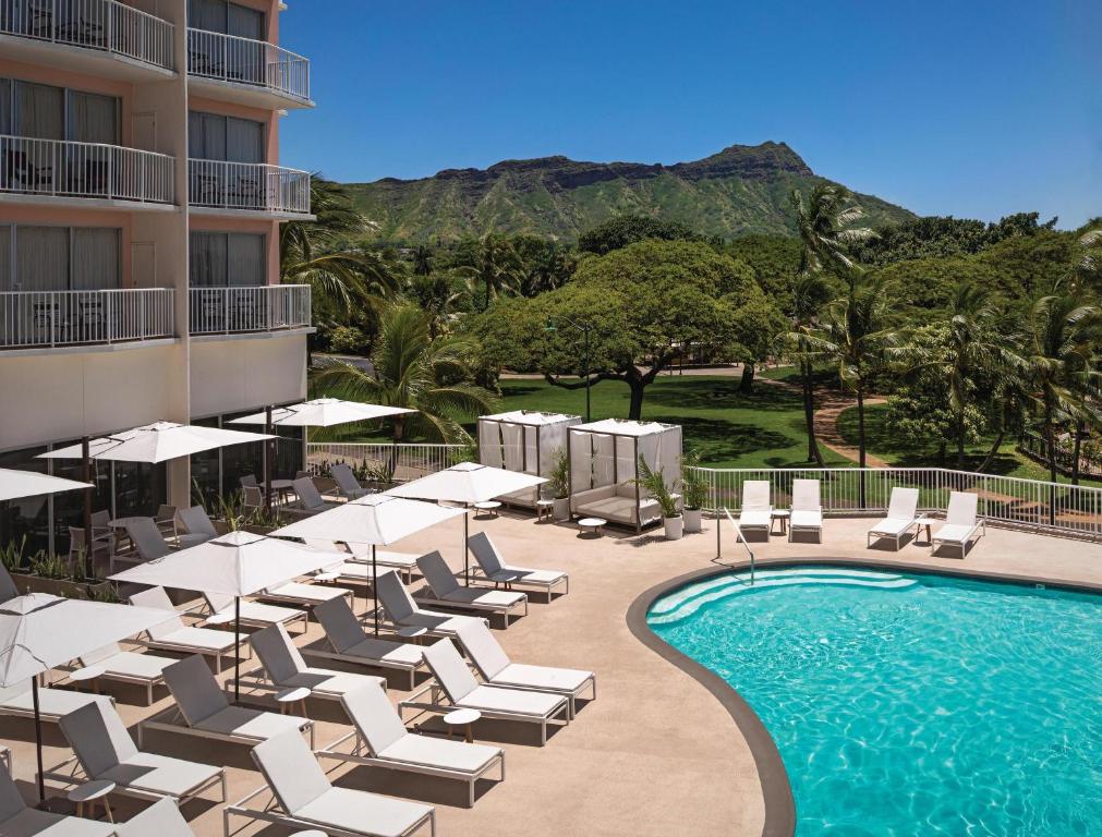 a swimming pool with lounge chairs and umbrellas next to a hotel at Park Shore Waikiki in Honolulu