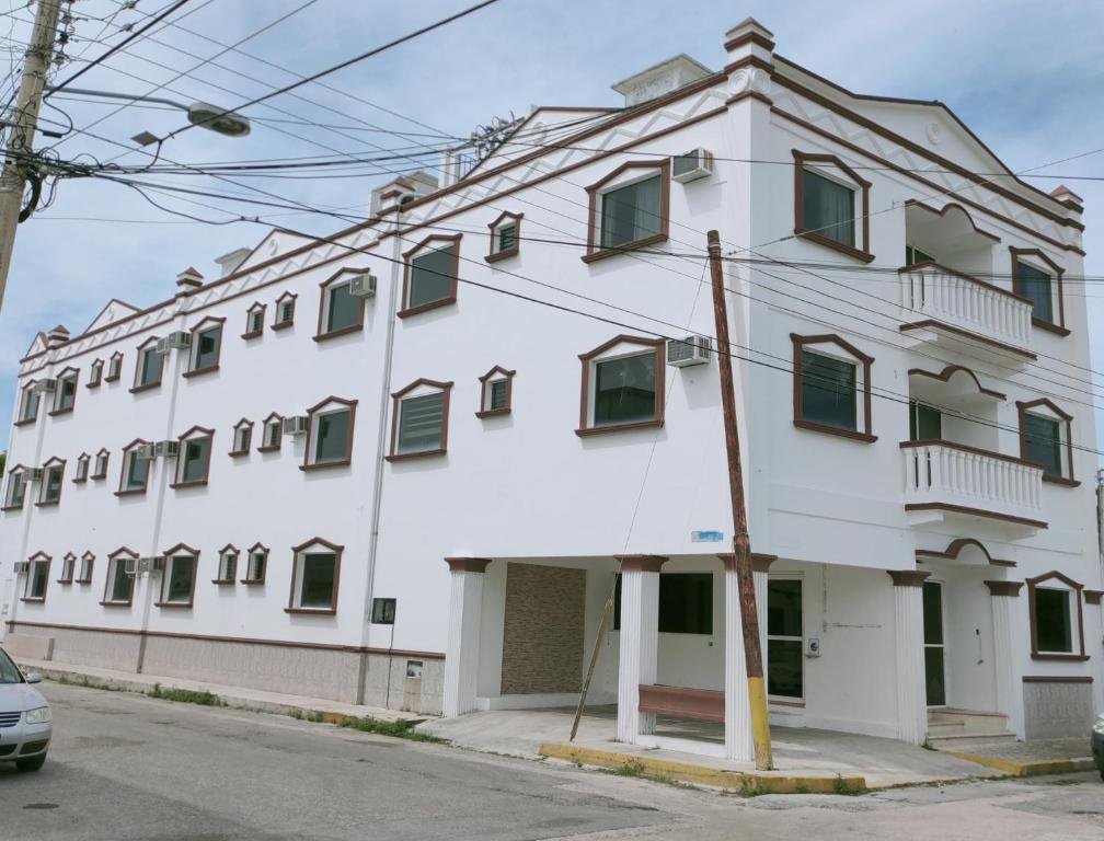 - un bâtiment blanc avec des fenêtres à volets verts dans l'établissement HOTEL CASA VEINTITRES, à Ciudad del Carmen