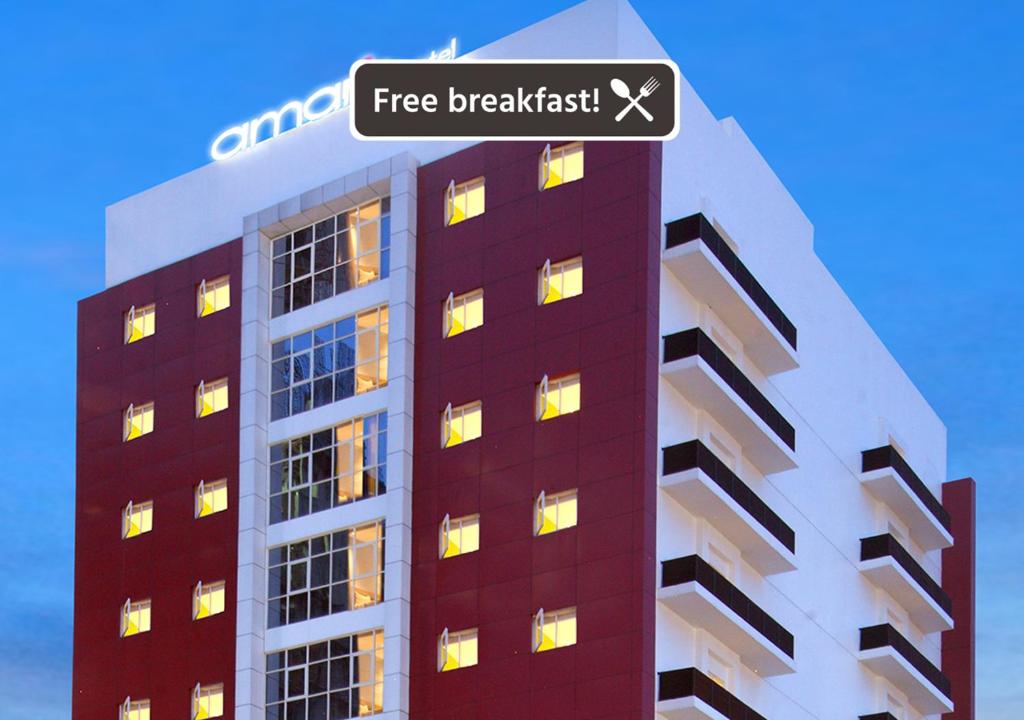 a tall building with a sign that reads free breakfast at Amaris Hotel Margorejo Surabaya in Surabaya