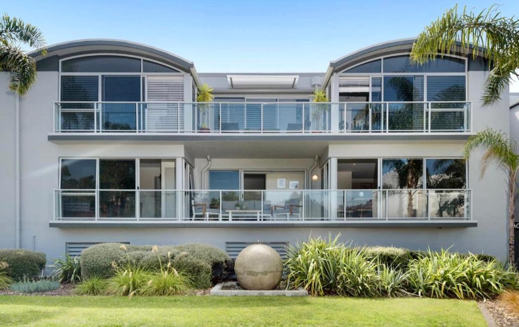 a large white house with a lot of windows at Modern Beach Apartment with Pool & Location in Mount Maunganui