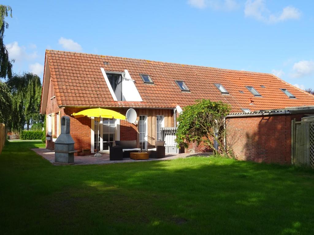 a brick house with a yellow umbrella in the yard at Huus an`t Koornfeld, Urlaub an der Nordsee im Herzen von Ostfriesland, Nahe Norden-Norddeich in Osteel