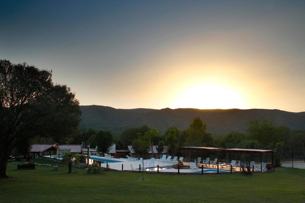 a large swimming pool in a park with the sun setting at Complejo el Paine in Villa General Belgrano