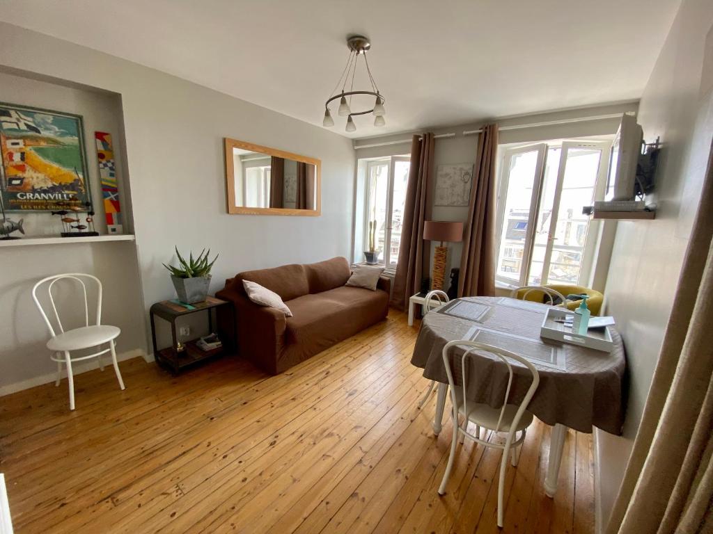 uma sala de estar com uma mesa e um sofá em Le Petit Logis - Vue Mer em Granville