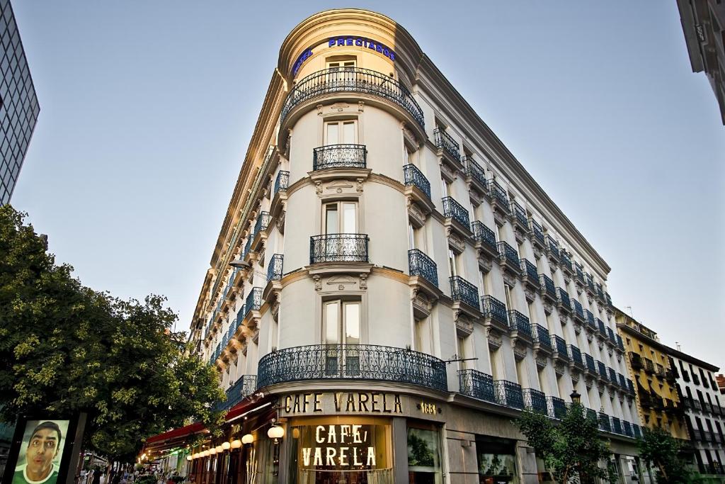 un gran edificio blanco con un cartel delante en Preciados en Madrid