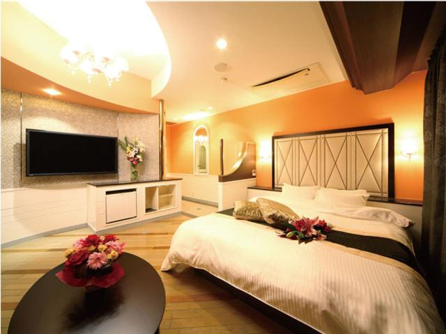 ein Schlafzimmer mit einem großen Bett und einem Flachbild-TV in der Unterkunft シーライフリゾートホテル in Ashiya