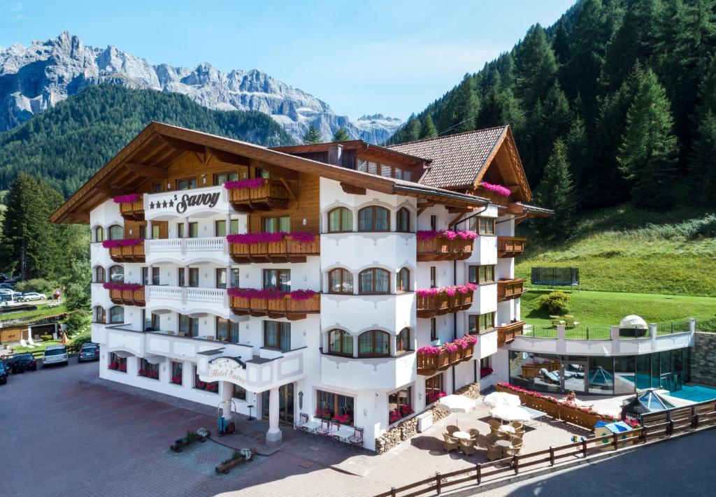 ein Hotelgebäude mit Pool und Bergen im Hintergrund in der Unterkunft Savoy Dolomites Luxury & Spa Hotel in Wolkenstein in Gröden