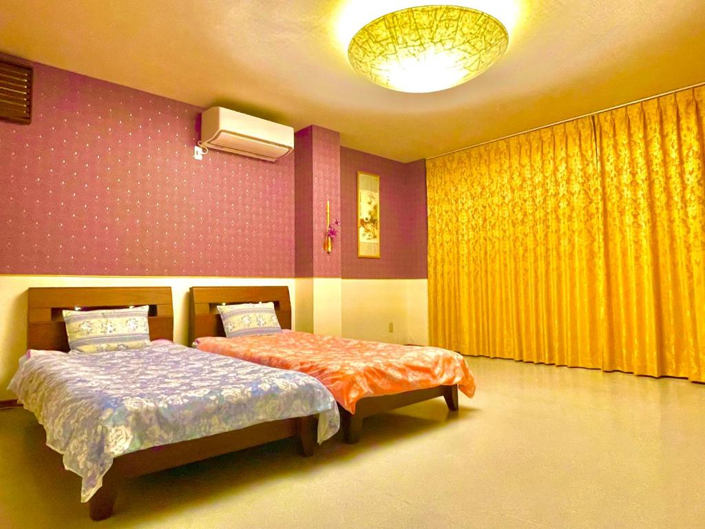 犬山市にある犬山モダンルームのベッドルーム1室(ベッド2台、黄色のカーテン付)