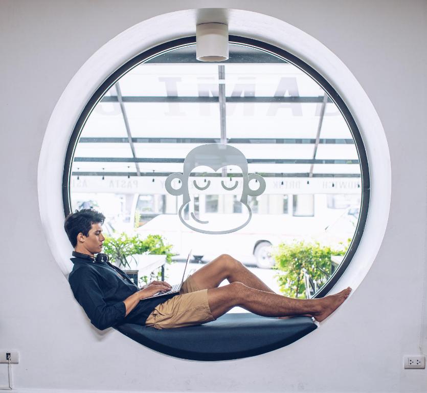 a man sitting in a hammock in a window at Blu Monkey Hub and Hotel Phuket Town- Free All Day Coworking space in Phuket Town