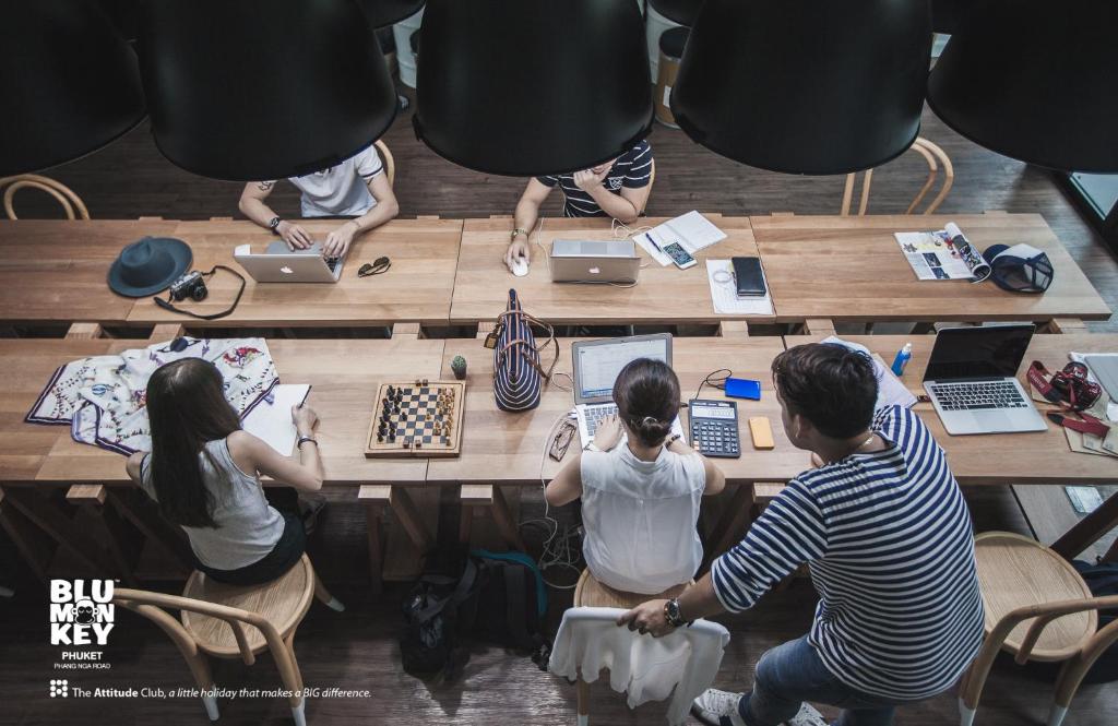 a group of people sitting at a table with laptops at Blu Monkey Hub and Hotel Phuket Town- Free All Day Coworking space in Phuket Town