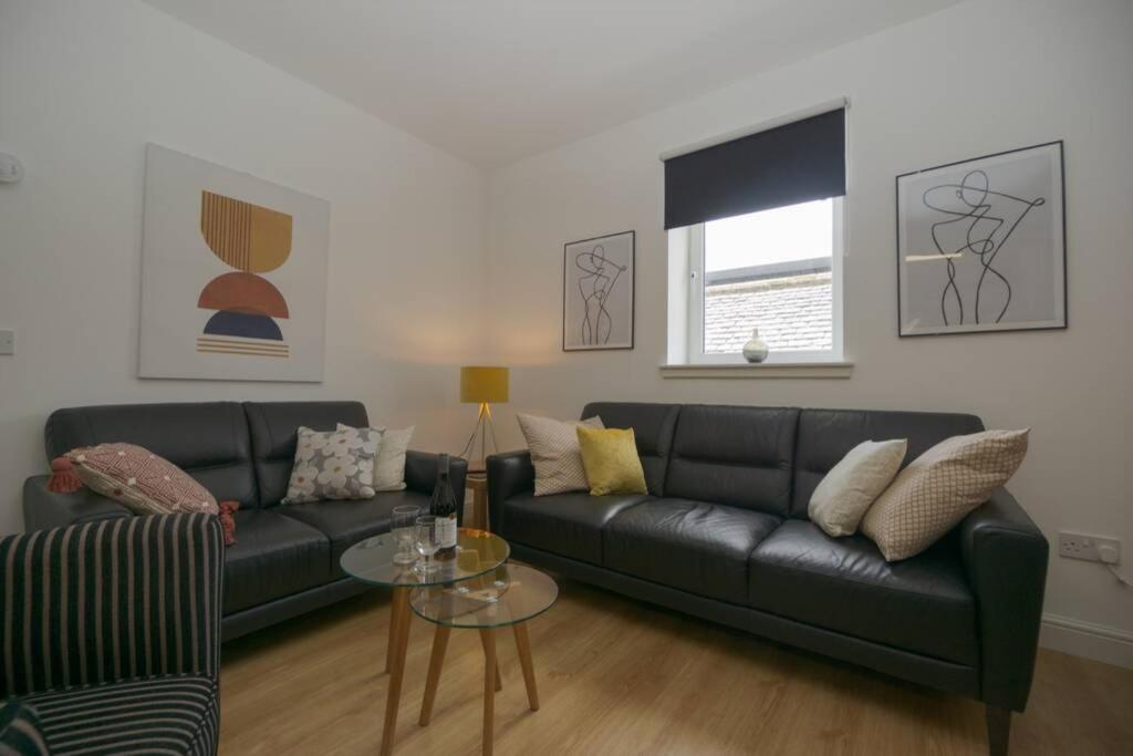 a living room with a black couch and a table at Town centre 4xbed 4xbath apartment in Elgin