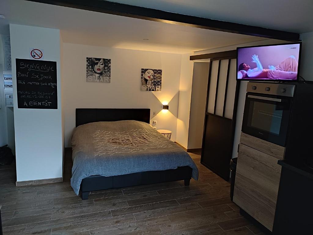 a bedroom with a bed and a flat screen tv at Charmante petite maison cosy style industriel in Longuenesse