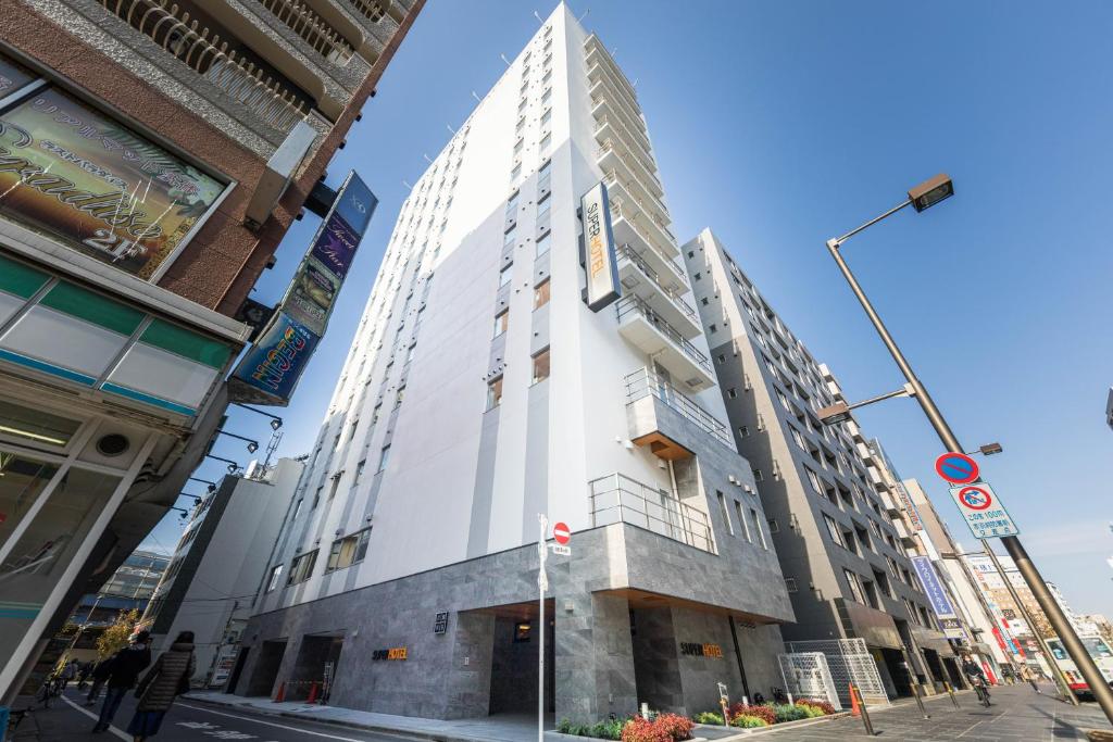 a tall white building on the corner of a street at Super Hotel Tokyo Akabane Eki Minamiguchi in Tokyo