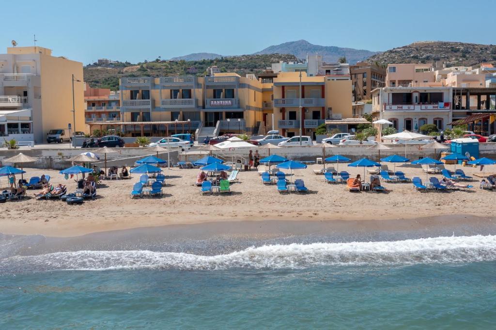 a beach with chairs and umbrellas and people on it at Zantina in Rethymno