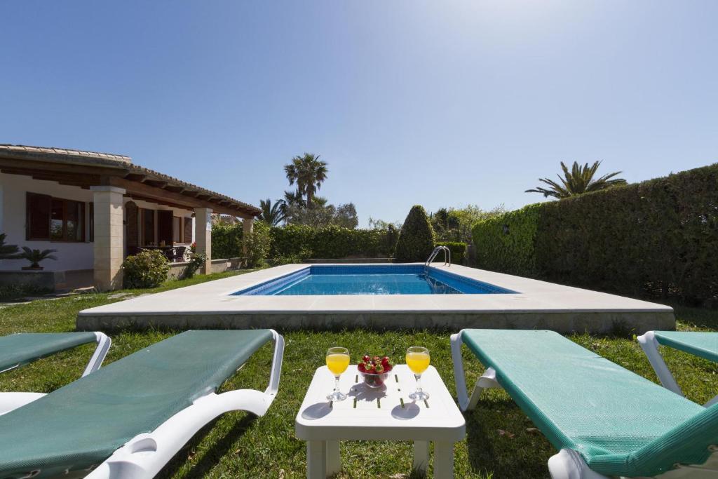 una mesa con 2 sillas junto a una piscina en Villa Jaume, en Pollensa