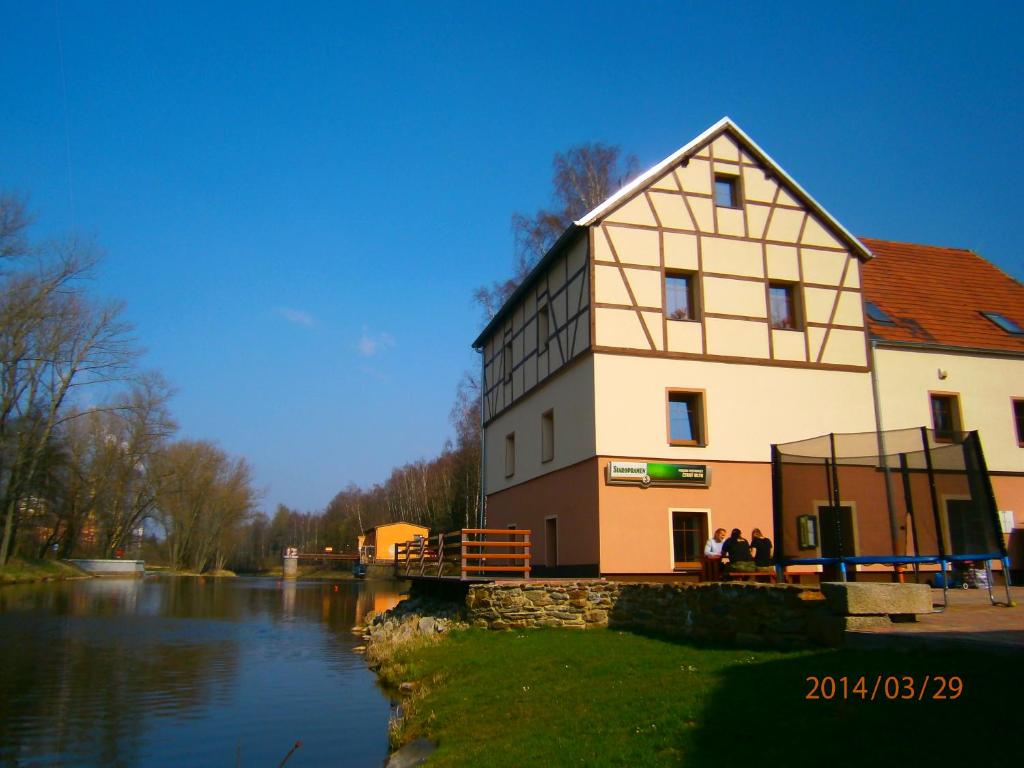 a large building next to a body of water at Penzion CERNY MLYN SOKOLOV in Březová