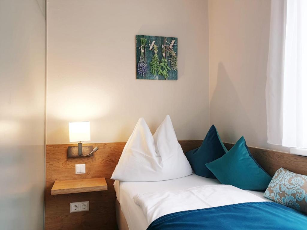 a bedroom with a bed with blue and white pillows at Hotel Garni Wurzer in Velden am Wörthersee