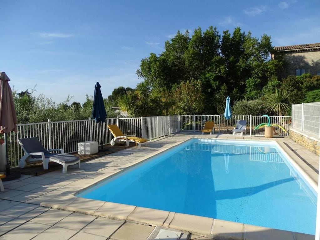 une piscine avec chaises et parasols sur un patio dans l'établissement Maison cosy à Cardet avec piscine, à Cardet