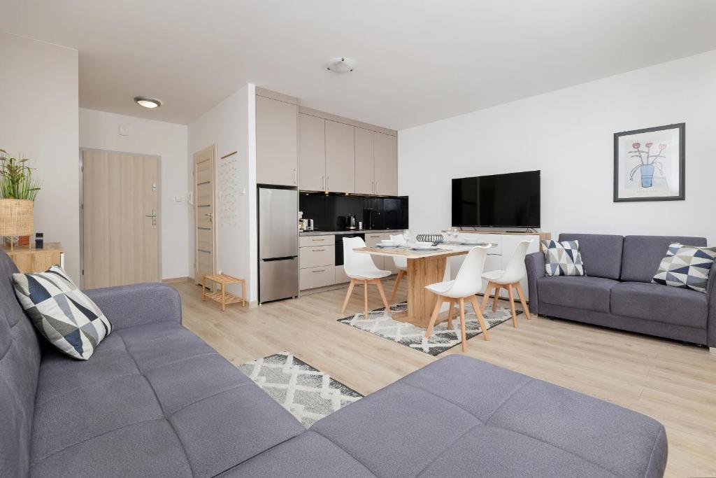 a living room with a couch and a table at Apartament Holiday B 101 in Pobierowo