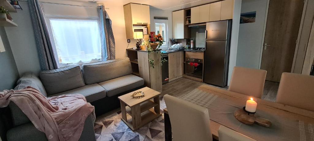 a living room with a couch and a table with a candle at Mobilhome 2 ch,1 salon 40m2 de Charme dans camping *** in Saint-Julien-en-Born