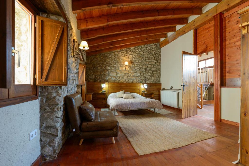 een slaapkamer met een bed, een bank en een stoel bij Suite deluxe en casa rural in Bas