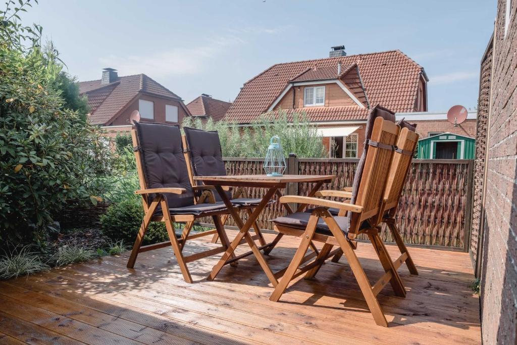 2 sillas y una mesa de madera en una terraza en Haus am Teich, en Hooksiel