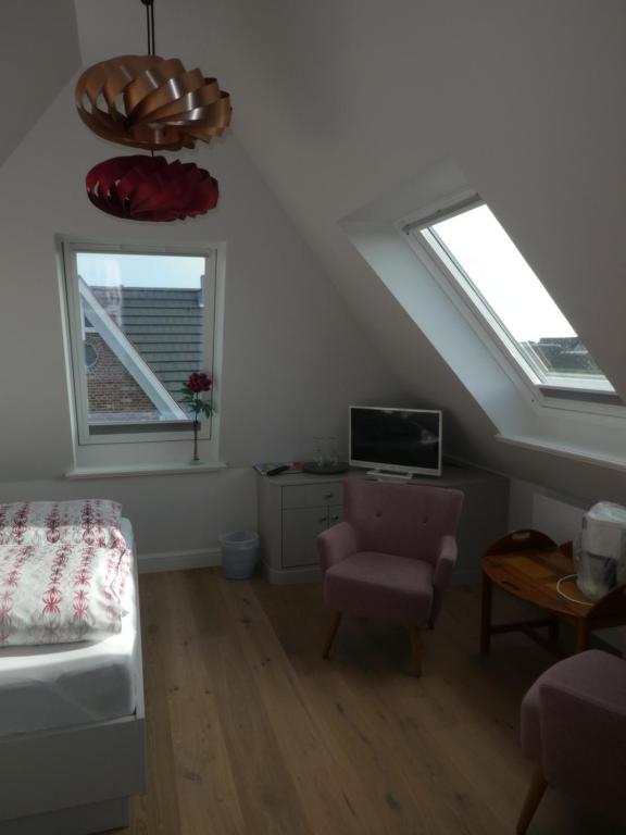 a bedroom with two windows and a bed and a chair at Haus Svenja in Westerland (Sylt)
