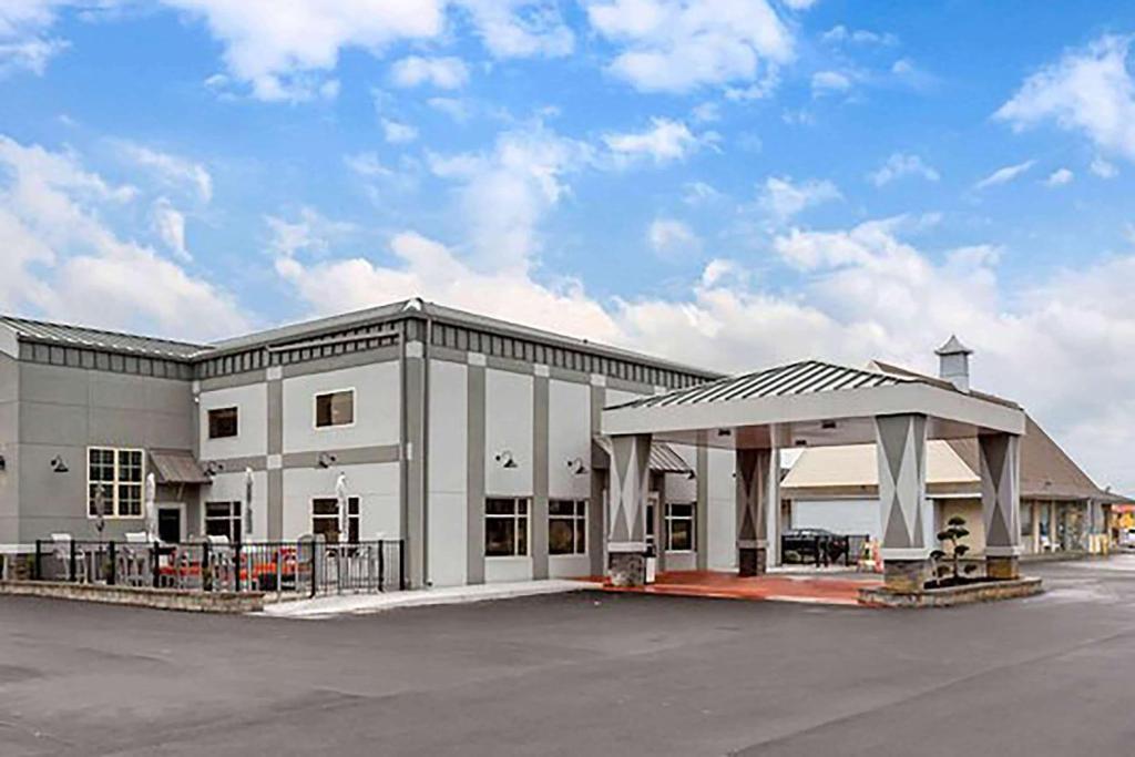a large white building with a parking lot at Days Inn &amp; Suites by Wyndham Bowling Green in Bowling Green