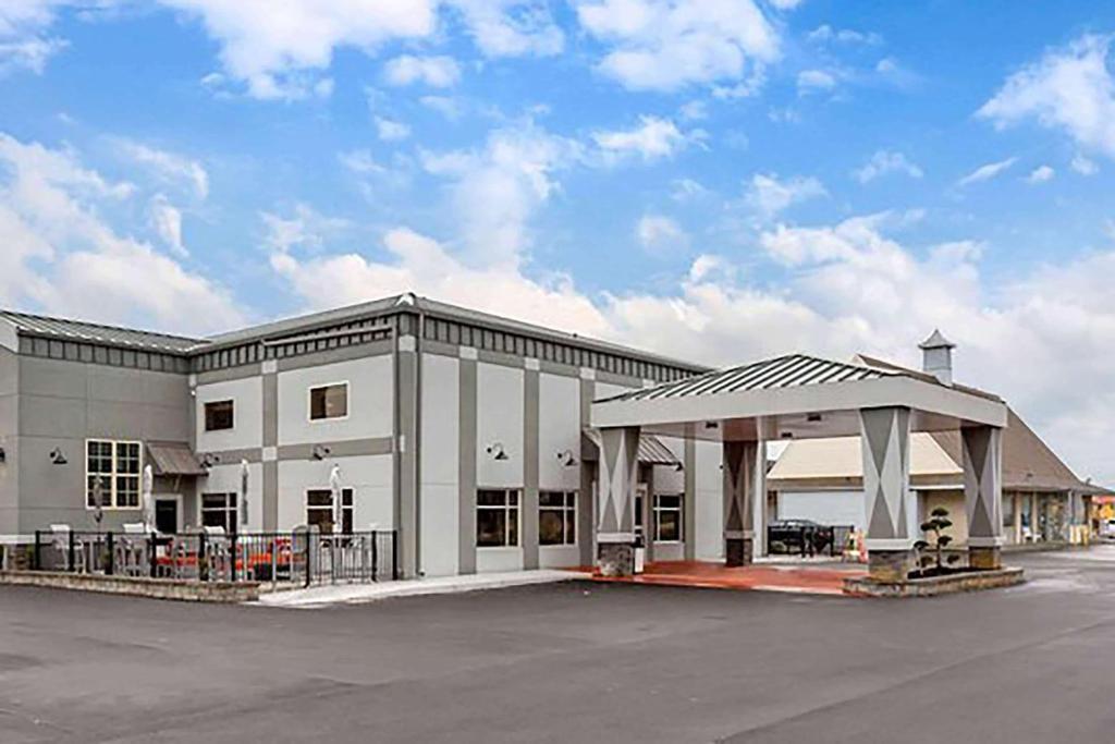 a large white building with a parking lot at Days Inn & Suites by Wyndham Bowling Green in Bowling Green