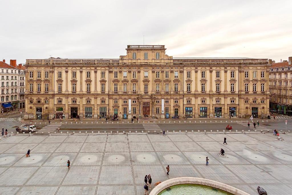un grand bâtiment avec une fontaine devant lui dans l'établissement Host inn Lyon - Appartement de Luxe aux Terreaux & Jacuzzi, à Lyon