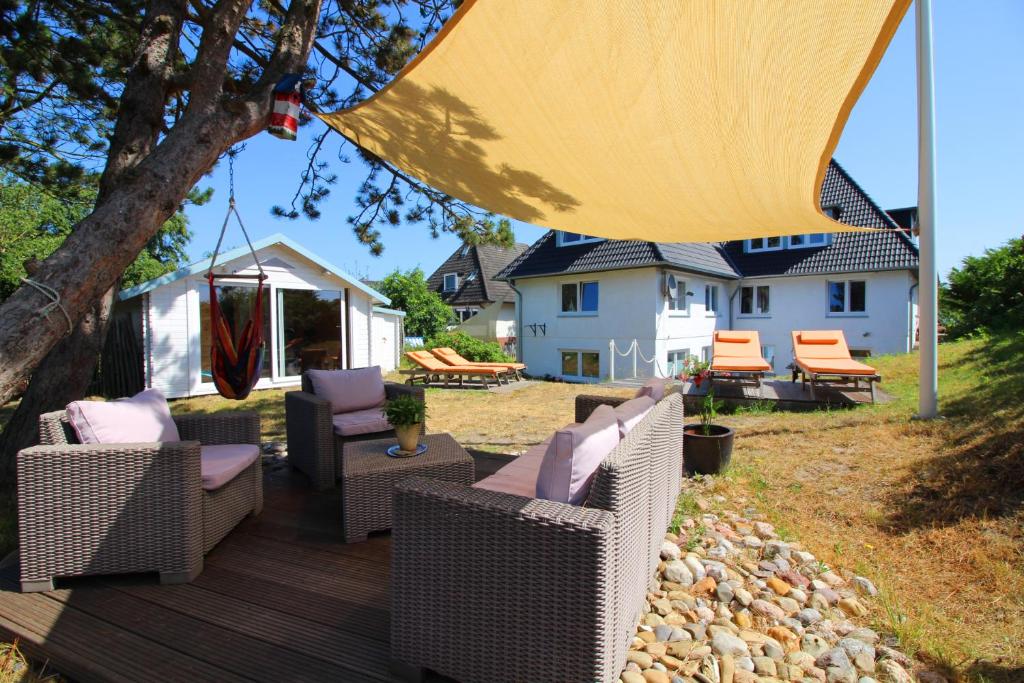 una terrazza in legno con sedie e ombrellone di GROßE-WILDE-BETTEN a Wittdün