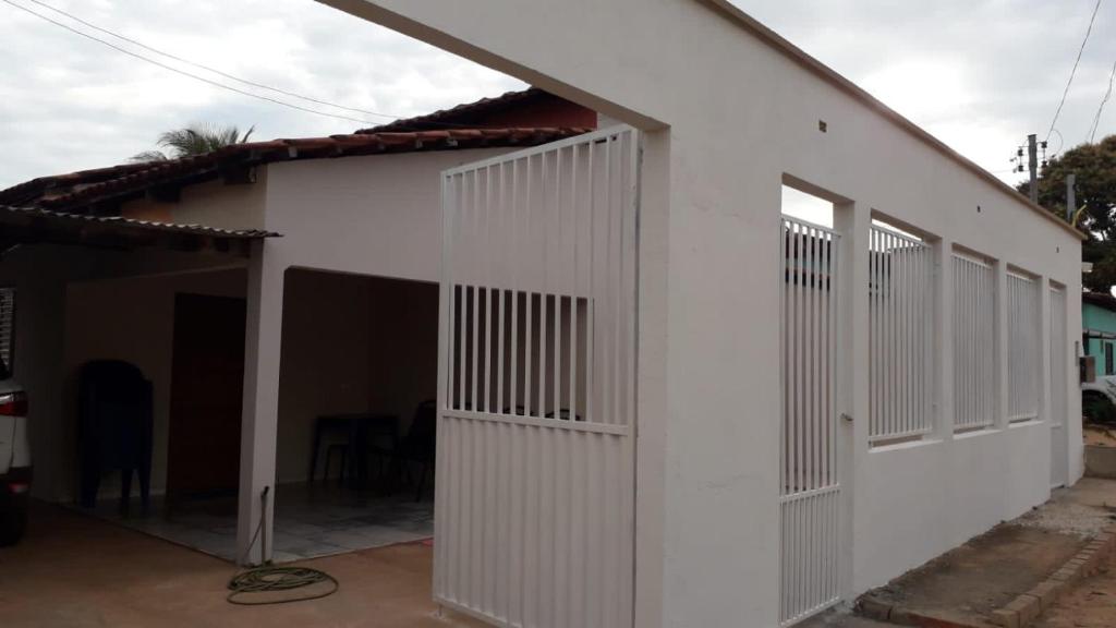 um edifício branco com um portão e uma garagem em CASA DE TEMPORADA NO JALAPÃO (CAP 11 PESSOAS) em Mateiros