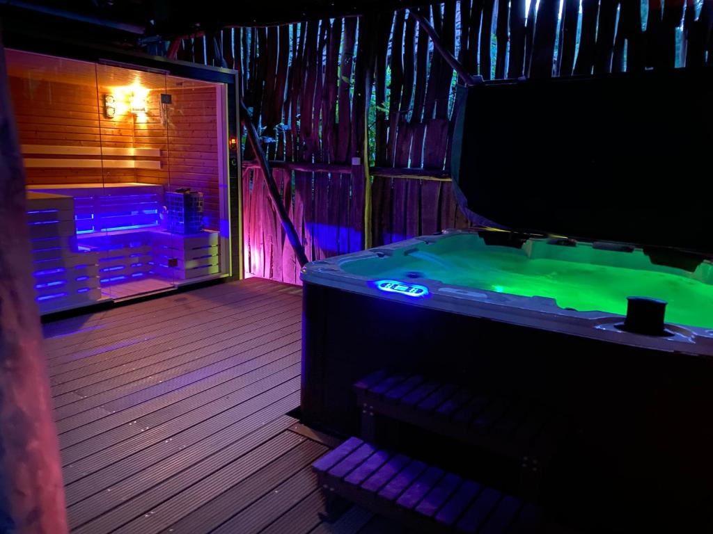 Habitación con bañera con luces verdes y moradas. en BNCK Wellness Residence, en Sátoraljaújhely