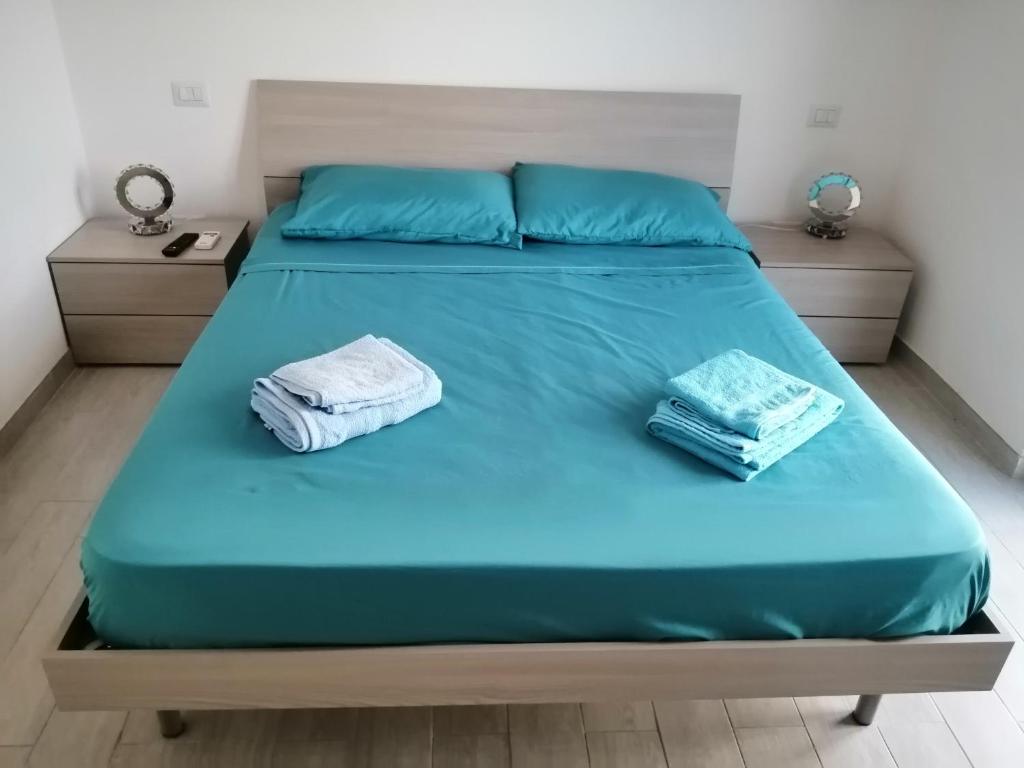 un letto con lenzuola blu e due asciugamani sopra di appartamento sapore di mare a Pozzallo