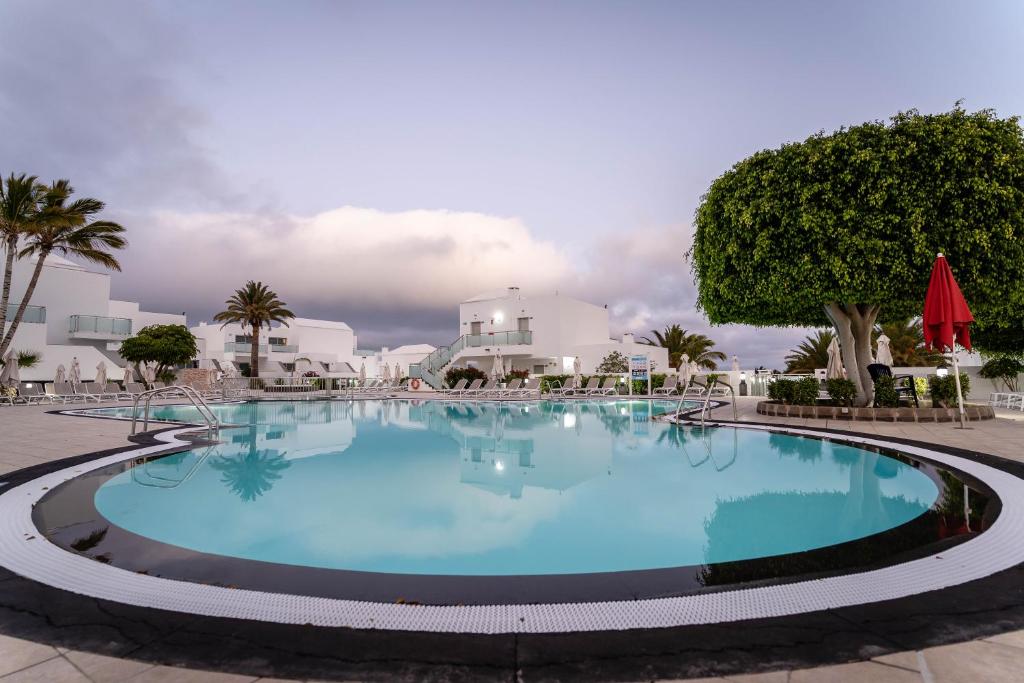 a large pool in a resort with palm trees and buildings at Hotel Lanzarote Village in Puerto del Carmen