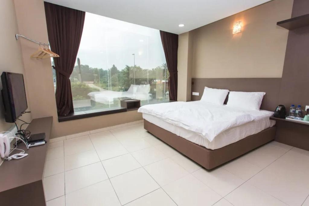 - une chambre avec un lit et une grande fenêtre dans l'établissement Tropika Garden Hotel, à Johor Bahru