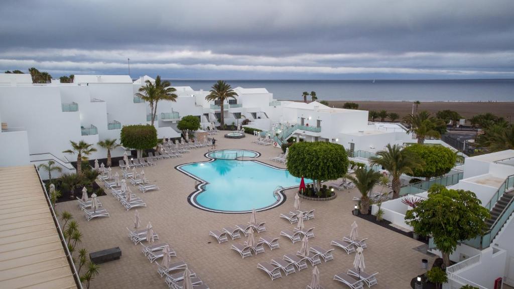 an aerial view of a resort with a pool and chairs at Hotel Lanzarote Village in Puerto del Carmen