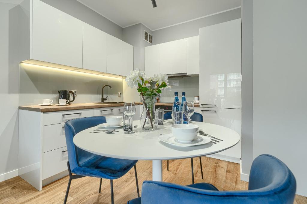 eine weiße Küche mit einem weißen Tisch und blauen Stühlen in der Unterkunft EXCLUSIVE FORTY Apartments in Stettin