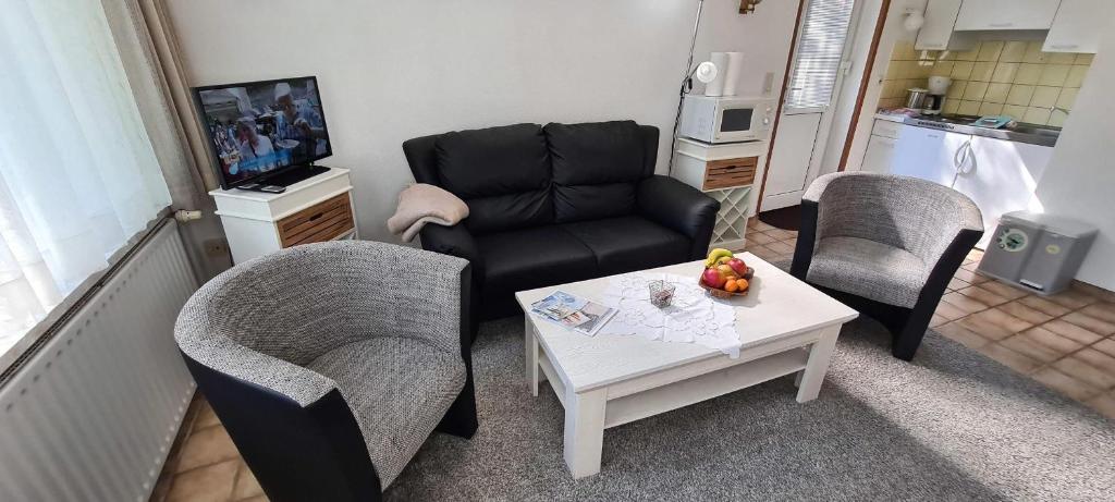 Una sala de estar con un sofá, una mesa y sillas. en FeWo-Hennings, en Olsdorf