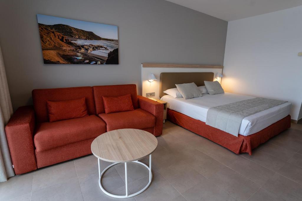 a bedroom with a bed and a couch and a table at Hotel Lanzarote Village in Puerto del Carmen