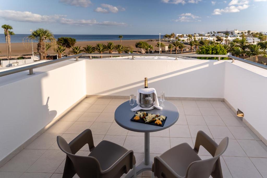 a table on a balcony with a view of the beach at Hotel Lanzarote Village in Puerto del Carmen