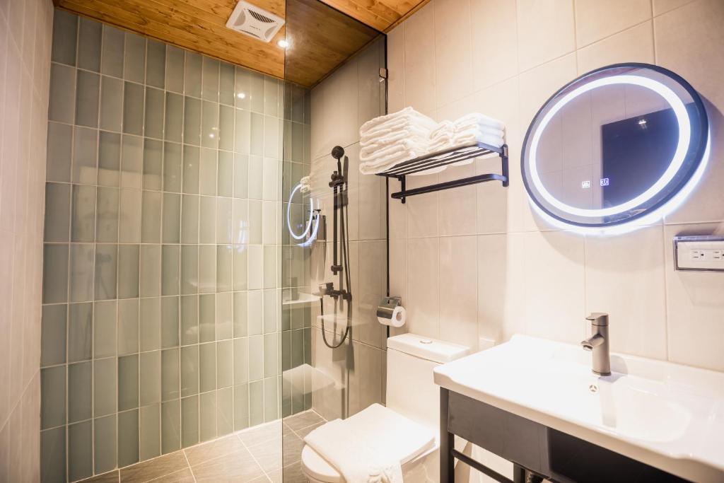 W łazience znajduje się prysznic, umywalka i lustro. w obiekcie Traveller-Inn Day Moon Hotel w mieście Taidong