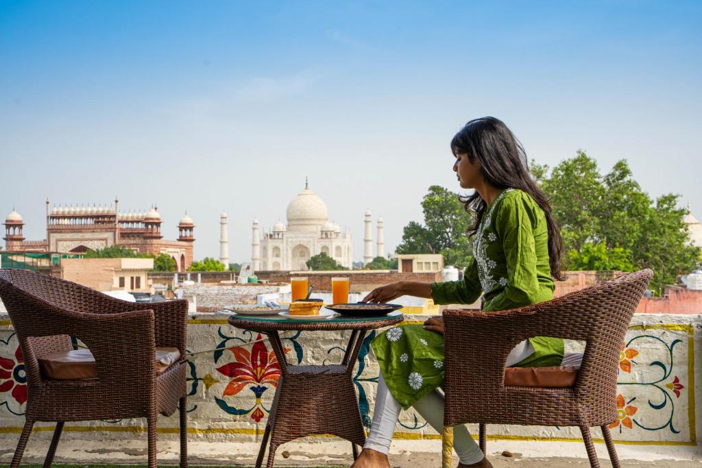Eine Frau, die an einem Tisch vor einem Gebäude sitzt. in der Unterkunft Joey's Hostel Agra in Agra