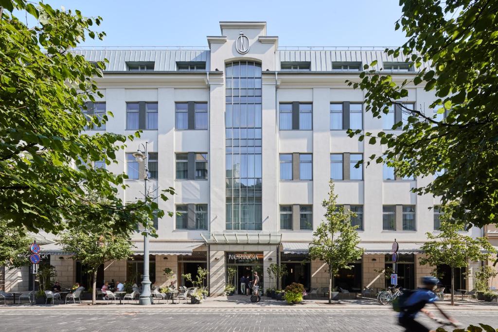 un hombre montando una bicicleta delante de un edificio en Neringa Hotel en Vilna