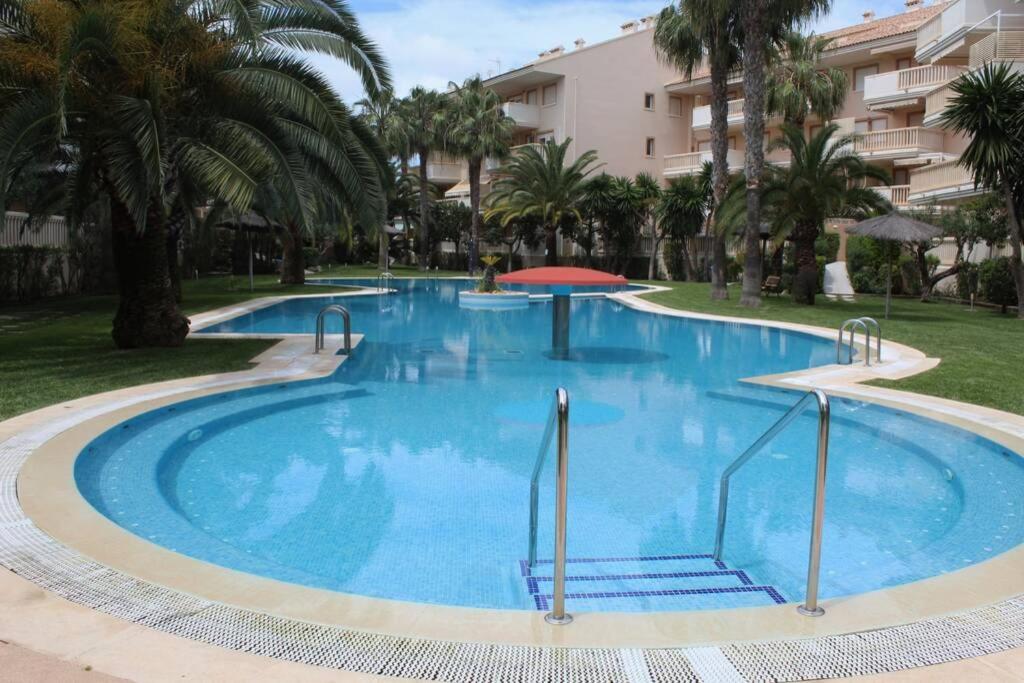 une grande piscine bleue avec des palmiers et un bâtiment dans l'établissement Javea Holydays, à Jávea