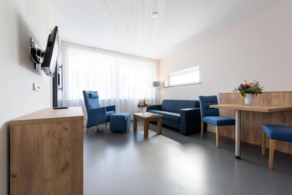un soggiorno con sedie blu e TV di Droomvakanties Egmond Appartement van Speijk a Egmond aan Zee