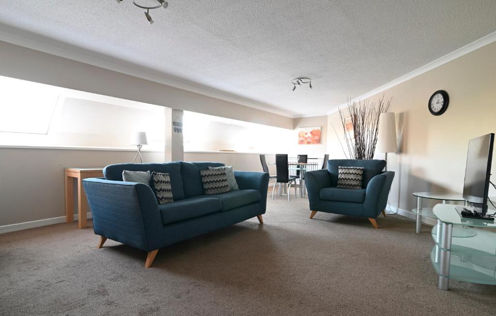 uma sala de estar com duas cadeiras azuis e uma televisão em Fabulous stylish flat in Merchant City & Free Secure Parking em Glasgow