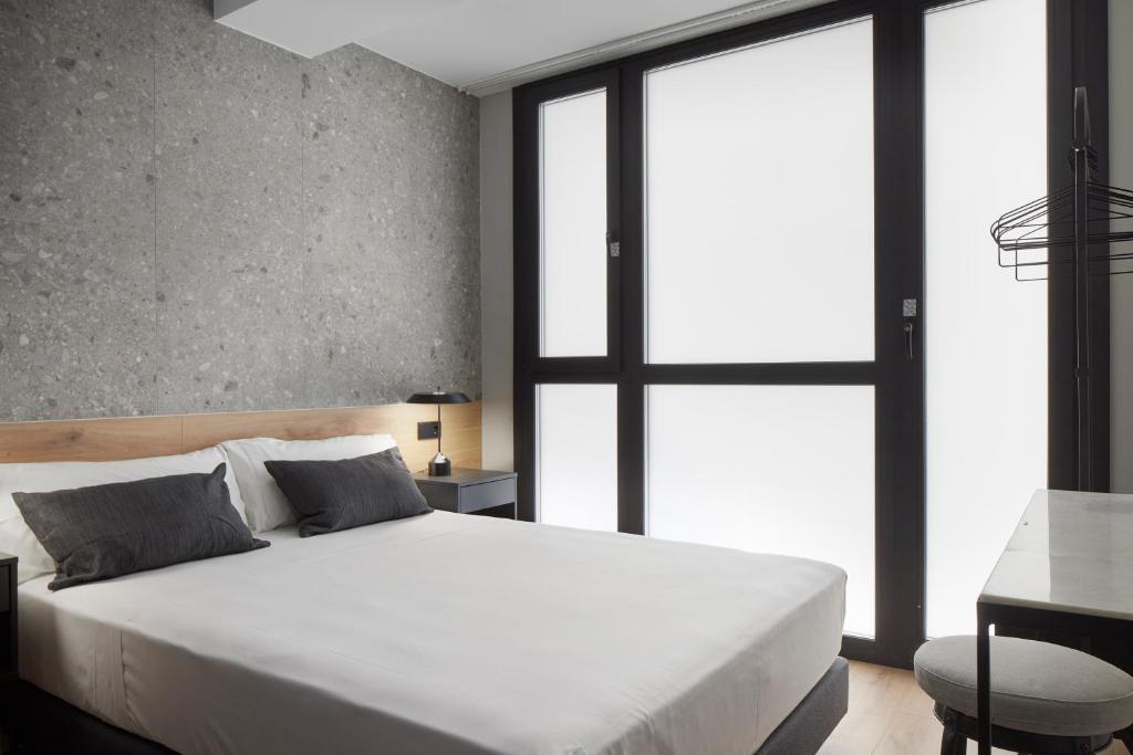 a bedroom with a large white bed and a desk at Hostal Espoz y Mina in Pamplona