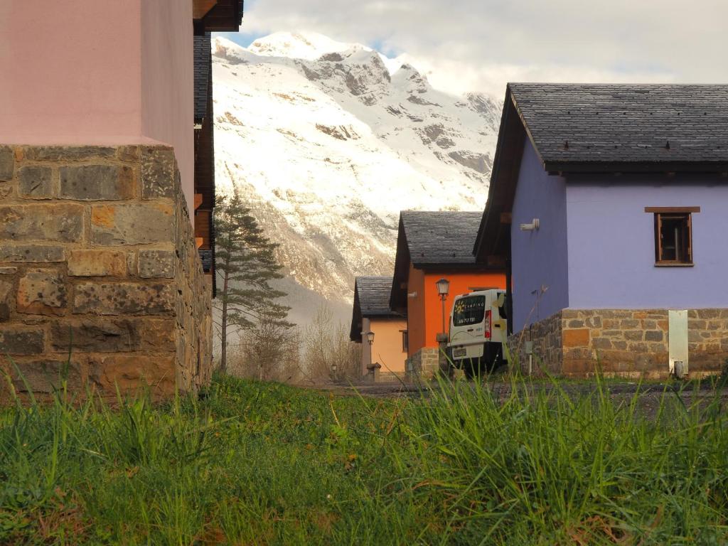 un grupo de casas con una montaña cubierta de nieve en el fondo en Camping Pineta, en Bielsa
