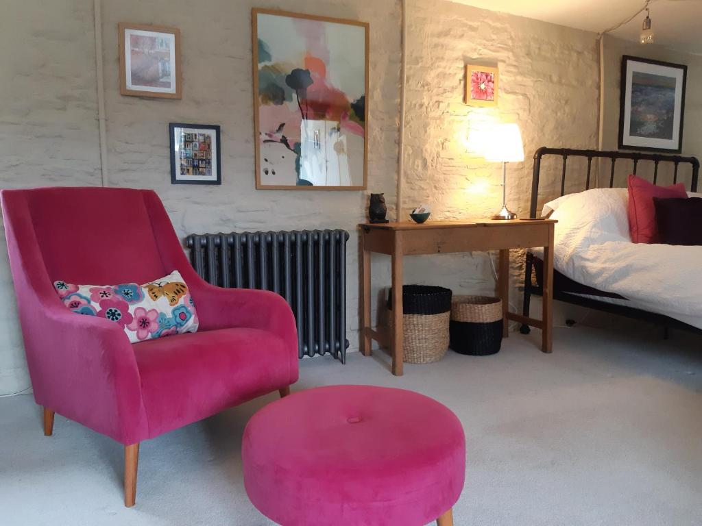 a bedroom with a red chair and a pink stool at Huberts, West End Farm, Fosse Lane, Poolbridge Road, Blackford, Wedmore in Wedmore